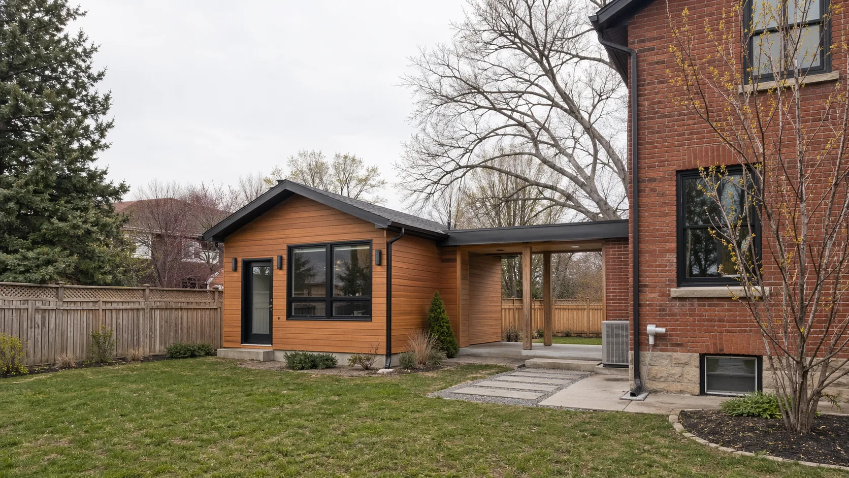 A detached backyard additional residential unit behind a London Ontario house